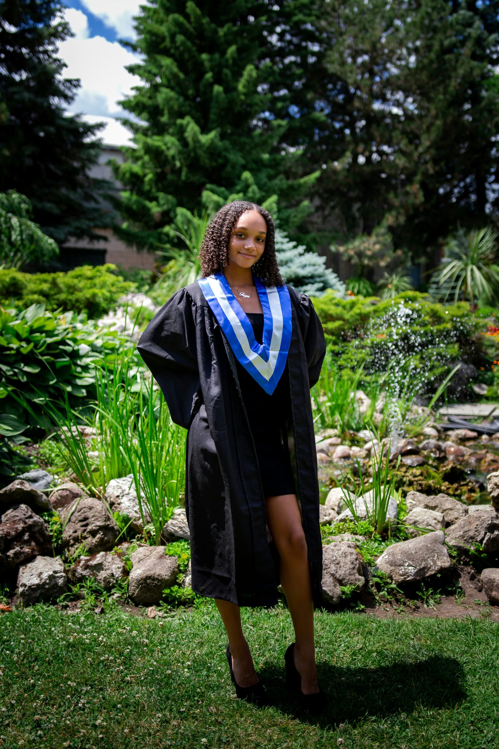 woman in black and blue academic dress standing on rocky ground during daytime